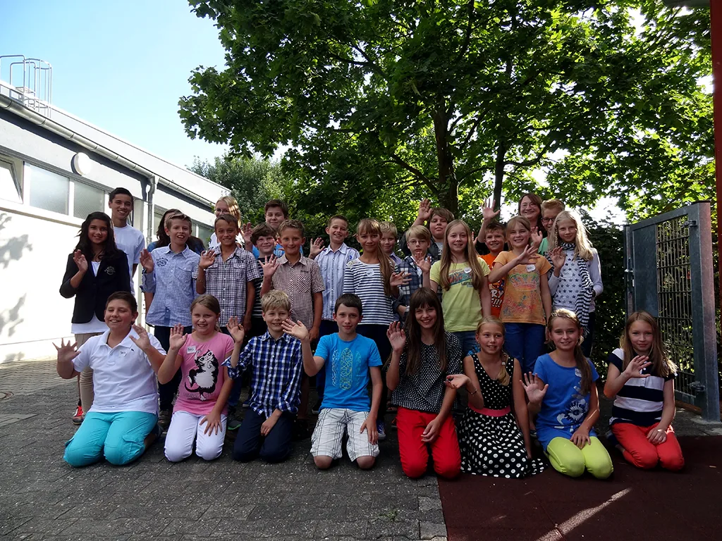 Klassenfoto einer neuen fünften Klasse vor der Schulhofmauer.